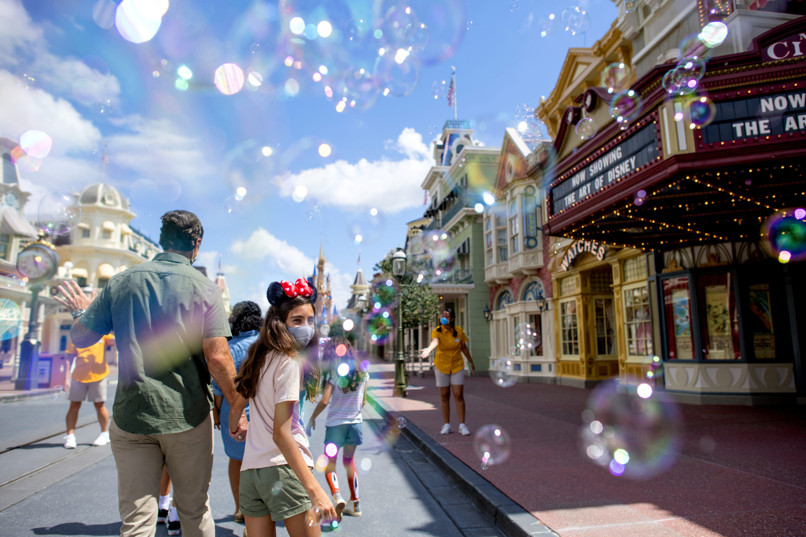 Bubbles surround a mask-wearing family as they walk down Main Street, USA and head toward Cinderella Castle